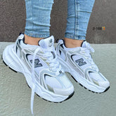 Tenis NB530 en color blanco y negro con diseño moderno y suela premium. Combinados con un outfit casual, mostrando su versatilidad.